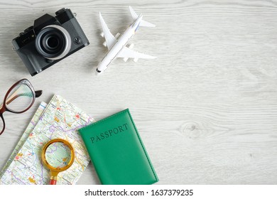 Travel planning concept. Top view traveler accessories, retro style camera, map with magnifying glass, passport, glasses, airplane model on wooden table. Travel agency banner design template