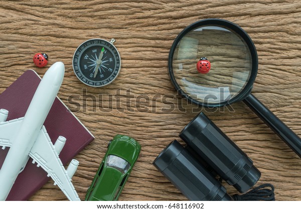 travel planning road trip concept with toy\
airplane, passport, compass, magnifying glass, binoculars, pencil,\
paper note and miniature car on wood\
table.