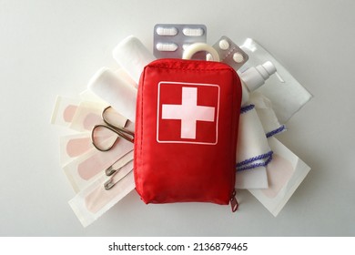 Travel portable first aid bag full of objects and tools for minor cures on white table. Top view. Horizontal composition
