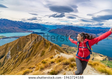 Travel post Covid-19 concept. Pent-up traveling demand concept. Hiker jumping of joy funny - woman hiking in New Zealand laughing having fun, joyful and aspirational at Roys Peak, South Island.