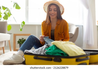 Travel preparation. Cheerful young Caucasian woman packing suitcase, getting ready for vacation at home, copy space. Millennial female going on tourist trip, happy about abroad adventure