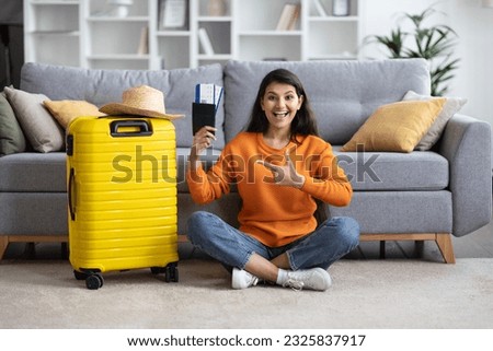 Travel preparation. Happy young eastern woman traveller packing suitcase, getting ready for vacation at home, copy space, going on tourist trip, showing passport, flight tickets and gesturing