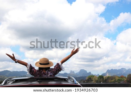 travel, Rear view of young happy people, road trip and people concept - happy young woman wearing hat and raising their arms up in convertible car