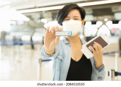 Travel restriction concept. A stylish asian woman smiling and show her negative swab testing before boarding. Rapid antigen test, SARS-CoV-2, Covid -19, Check, Screening, Airport, Transportation.