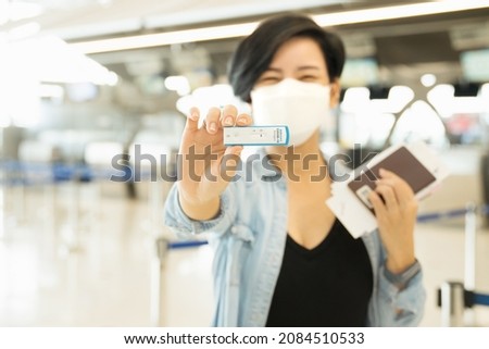 Travel restriction concept. A stylish asian woman smiling and show her negative swab testing before boarding. Rapid antigen test, SARS-CoV-2, Covid -19, Check, Screening, Airport, Transportation.