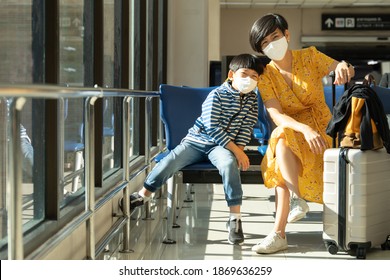Travel restriction during covid-19 pandemic concept. A beautiful asian mom and her little boy sit together in the Airport, they're wearing face mask to protect and prevent virus, Vaccination, Immune.