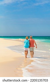 Travel Retired Couple Walking Barefoot Along Shoreline Of Tropical Island Beach Enjoying Togetherness On Romantic Getaway Bahamas 