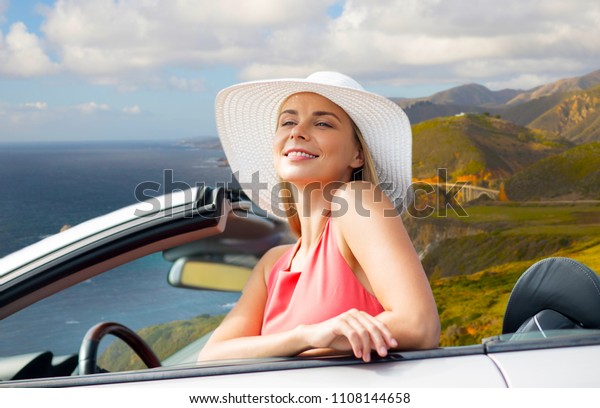travel, road trip and people\
concept - happy young woman wearing sun hat in convertible car over\
bixby creek bridge on big sur coast of california\
background