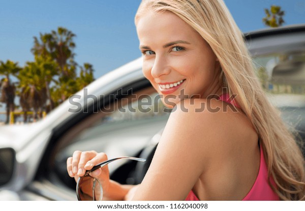 travel, road trip and people concept - close\
up of happy young woman in convertible car over venice beach\
background in\
california