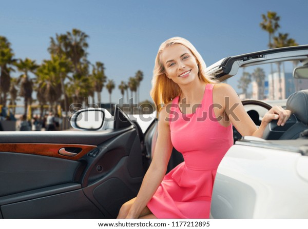 travel, road trip and people concept - happy\
young woman posing in convertible car over venice beach background\
in california