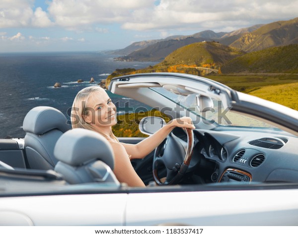 travel, road trip and people\
concept - happy young woman driving convertible car over bixby\
creek bridge on big sur coast of california\
background