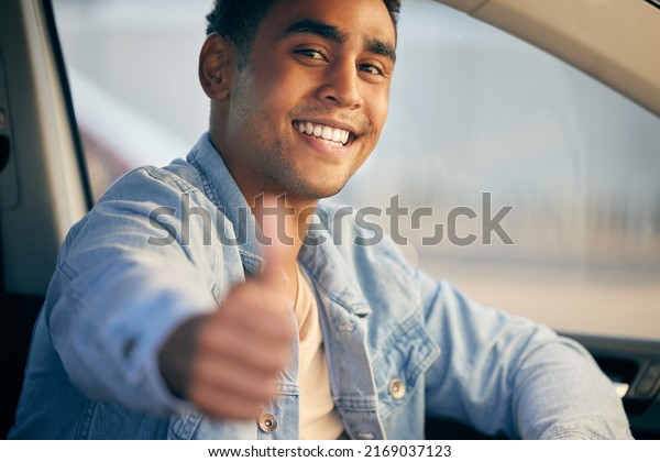 Travel safe. Shot of a young man showing thumbs up\
while traveling in a\
car.