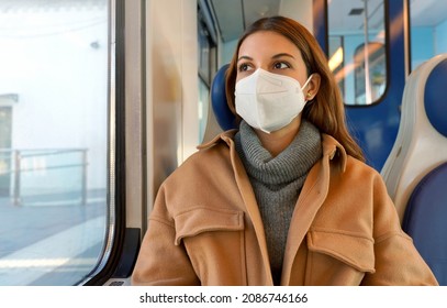 Travel safely on public transport. Young woman with KN95 FFP2 face mask looking through train window. Commuter passenger with protective mask travels sitting on train.