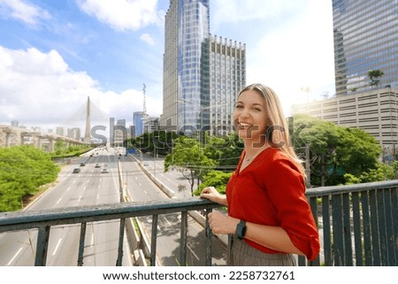 Travel in Sao Paulo, Brazil. Portrait of beautiful smiling girl with Sao Paulo cityscape and Ponte Estaiada bridge on the background, Sao Paulo, Brazil.