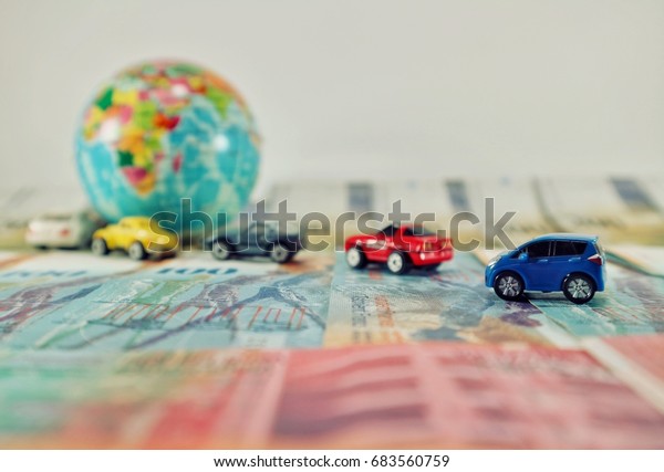 Travel and savings money\
concept, focus blue car and cars line queue to mini world globe on\
banknote