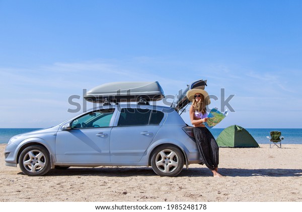 travel to the sea by car. the\
girl is looking for a road on the map. the car stopped on the\
beach