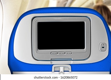 Travel Seat In Airplane Interior With Blank Inflight Entertainment System Screen In Headrest Against Plane Cabin Background. Back View Of Passenger Chair With Touchscreen. Copy Space Design Template