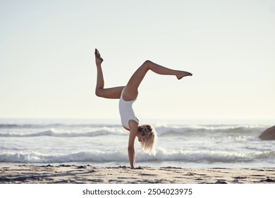 Travel, summer and girl with handstand on beach on vacation, energy and gymnastic skills with ocean waves. Woman, sea and upside down in swimwear on holiday in California, active and balance on sand. - Powered by Shutterstock