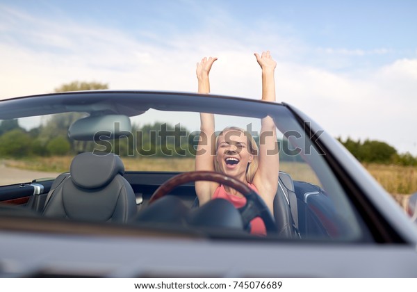 travel, summer holidays,\
road trip and people concept - happy young woman in convertible car\
enjoying sun
