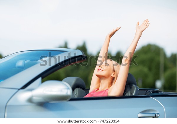 travel, summer holidays,\
road trip and people concept - happy young woman in convertible car\
enjoying sun