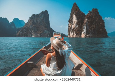 Travel summer vacation concept, Happy solo traveler asian woman with hat relax and sightseeing on Thai longtail boat in Ratchaprapha Dam at Khao Sok National Park, Surat Thani Province, Thailand - Shutterstock ID 2302449731