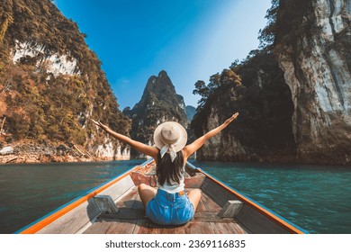 Travel summer vacation concept, Happy solo traveler asian woman with hat relax and sightseeing on Thai longtail boat in Ratchaprapha Dam at Khao Sok National Park, Surat Thani, Thailand - Powered by Shutterstock