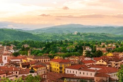 Travel Summer View From Hill To A Nice European Town With Amazing Buildings, Green Hills And Mountains With Amazing Cloudy Evening Sky On Background, Urban Sunset Landscape