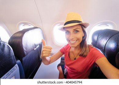 Travel And Technology. Young Woman In Plane Taking Selfie While Sitting In Airplane Seat.