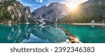 Travel theme: Panoramic view of Lago di Braies, Pragser Wildsee in the Dolomites. View of the whole green-blue lake through wooden boats on the mountain peak and the setting sun. 