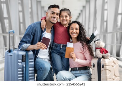 Travel Together. Portrait Of Happy Arab Parents And Daughter Relaxing In Airport With Baggage And Tickets, Young Middle Eastern Family Waiting For Flight At Terminal, Looking And Smiling At Camera