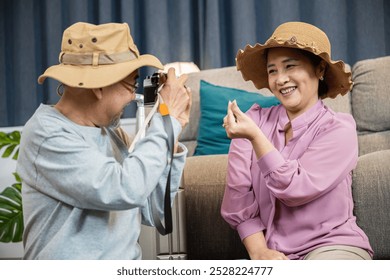 Travel and tourism. Asian couple old senior marry retired couple smiling taking photo by camera during luggage suitcase arranging for travel, Happy mature retired couple photography weekend holiday - Powered by Shutterstock