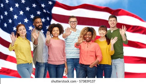 Travel, Tourism, Diversity, Ethnicity And People Concept - International Group Of Happy Smiling Men And Women Waving Hand Over American Flag Background