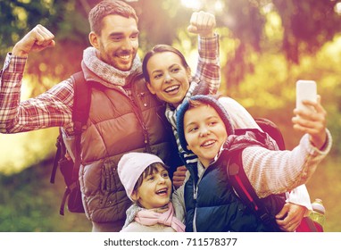 Travel, Tourism, Hike And Technology Concept - Happy Family With Backpacks Taking Selfie By Smartphone Outdoors