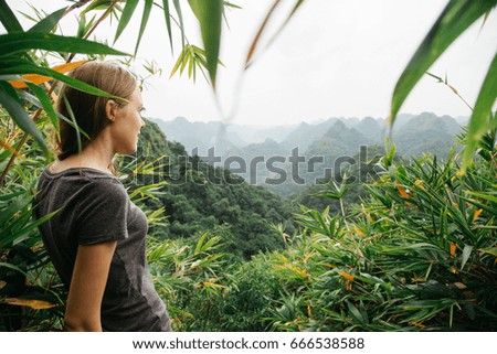 Travel, tourism and people concept - single woman is standing on top of a mountain and looking on the panorama of mountains 