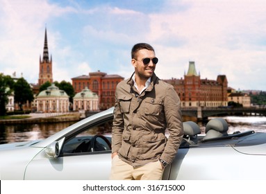 Travel, Tourism, Road Trip, Transport And People Concept - Happy Man Near Cabriolet Car Over City Of Stockholm In Sweden Background