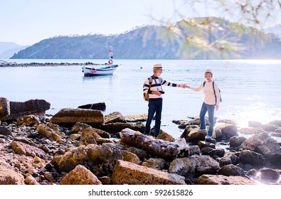 Travel And Tourism. Senior Family Couple Walking Together On Mediterranean Sea Beach.