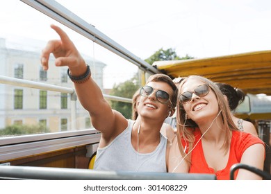 Travel, Tourism, Summer Vacation, Sightseeing And People Concept - Happy Teenage Couple In Sunglasses Traveling By Tour Bus And Listening To Music With Earphones