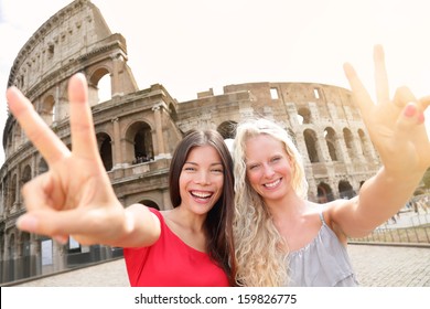 Travel tourist girl friends by Colosseum, Rome. Happy girlfriends tourists showing victory hand sign gesture in front of Coliseum. Beautiful young happy blonde girl and multiracial Asian woman, Italy. - Powered by Shutterstock