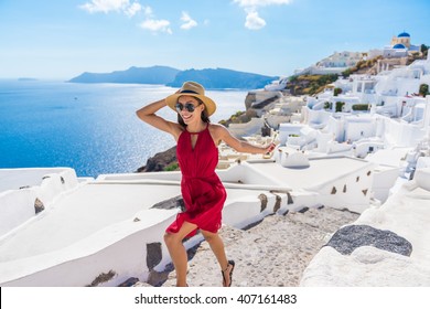 Travel Tourist Happy Woman Running Stairs Santorini, Greek Islands, Greece, Europe. Girl On Summer Vacation Visiting Famous Tourist Destination Having Fun Smiling In Oia. 