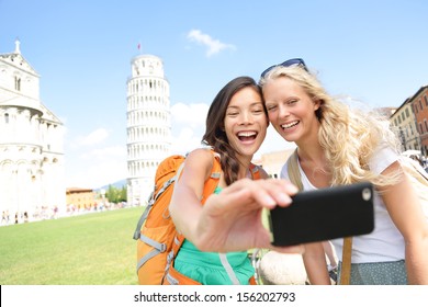 Travel Tourists Friends Laughing Taking Photo With Smartphone. Women Girlfriends Traveling In Europe Smiling Joyful Having Fun Taking Self-portrait Picture In Pisa By Leaning Tower Of Pisa, Italy.