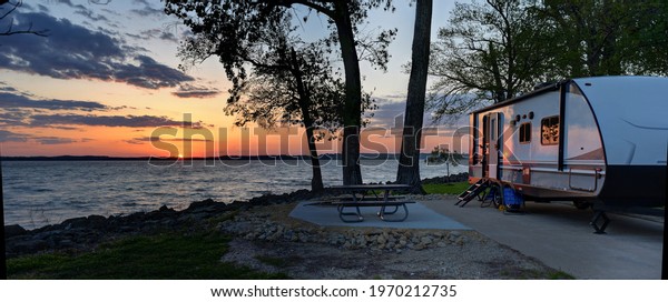 Travel trailer camping at sunset by the\
Mississippi river in Illinois at sunset\
panorama