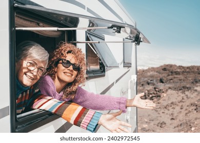 Travel and transport concept. Couple of smiling females friends or family at the window of the motorhome camper van enjoying road trip and vacation - Powered by Shutterstock