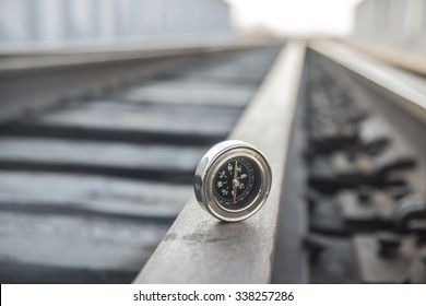 Travel Or Transportation Concept. Metal Modern Compass Lie On Wooden And Metal Railway In Perspective Background Empty Space For Inscription. No Train On Road. Direction Idea, Symbol, Sign