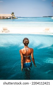 Travel Vacation - Beautiful Young Pretty Blonde Girl Back In Bikini On Her Perfect Sport Sexy Body Relax In Pool Near Paradise Beach At Tropical Caribbean Maldives Beach At Sunny Day In Hotel