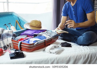 Travel And Vacation Concept, Happiness Young Man Packing A Lot Of His Clothes And Stuff Into Suitcase On Bed Prepare For Travel And Journey Trip In Holiday.