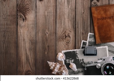 Travel And Vacation Concept.  Items On Aged Wooden Table. Vintage Film Camera, Old Photos, Roll, Sea Shells, Passport. Top View With Copy Space