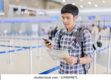 Travel Vacation Concept.Asian Man In Airport Or Train Station Using Travel App On A Smartphone Call Someone,Asia Male Tourist Reading Map While Waiting For Taxi Or Bus With A Bag, Ready For Journey 