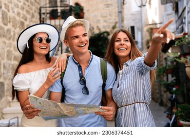 Travel, vacation and friendship concept. Group of smiling friends with city map exploring city - Powered by Shutterstock