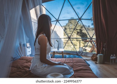Travel vacation glamping concept, Happy traveler asian woman relax inside a luxury camping dome tent in Mon Jam, Chiang Mai, Thailand