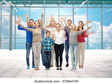 Travel, Vacation And People Concept - Group Of Happy People Or Big Family Waving Hands Over Airport Terminal Window And Sky Background